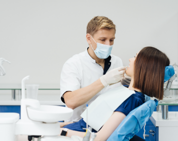 close-up-portrait-beautiful-young-lady-sitting-dental-chair-while-stomatologist-hands-sterile-gloves-holding-tooth-samples 1 (1)